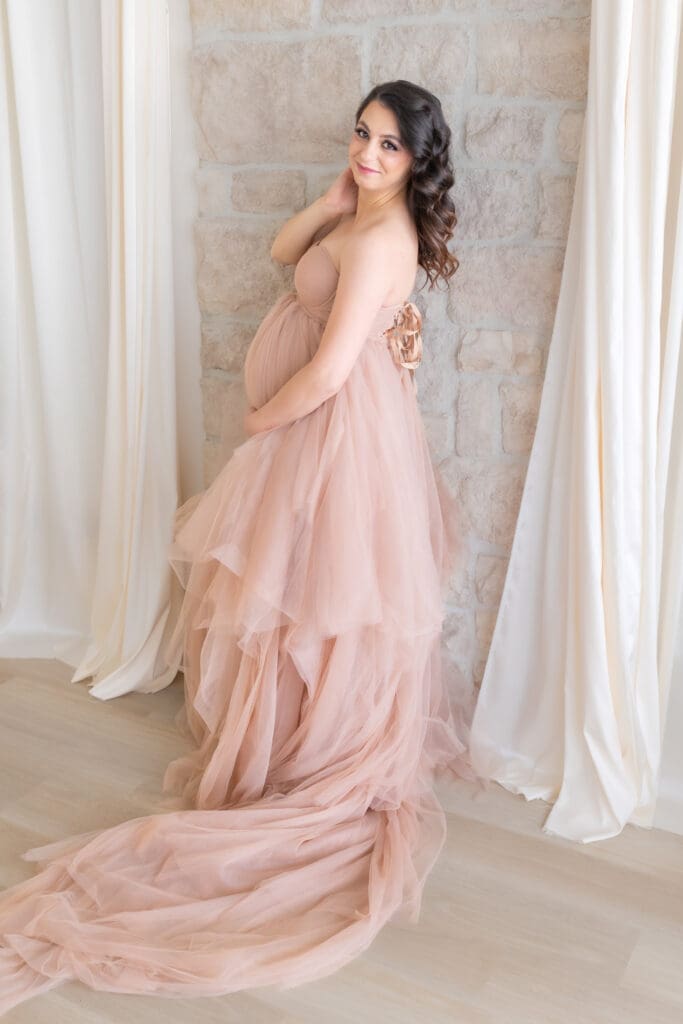 JimaMaternity photographer capturing silhouette of pregnant woman against sheer curtains