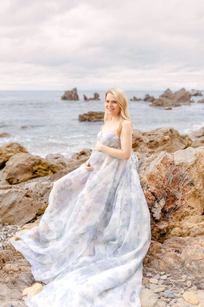 Pregnant woman in flowing gown cradling baby bump in Southern California maternity photography