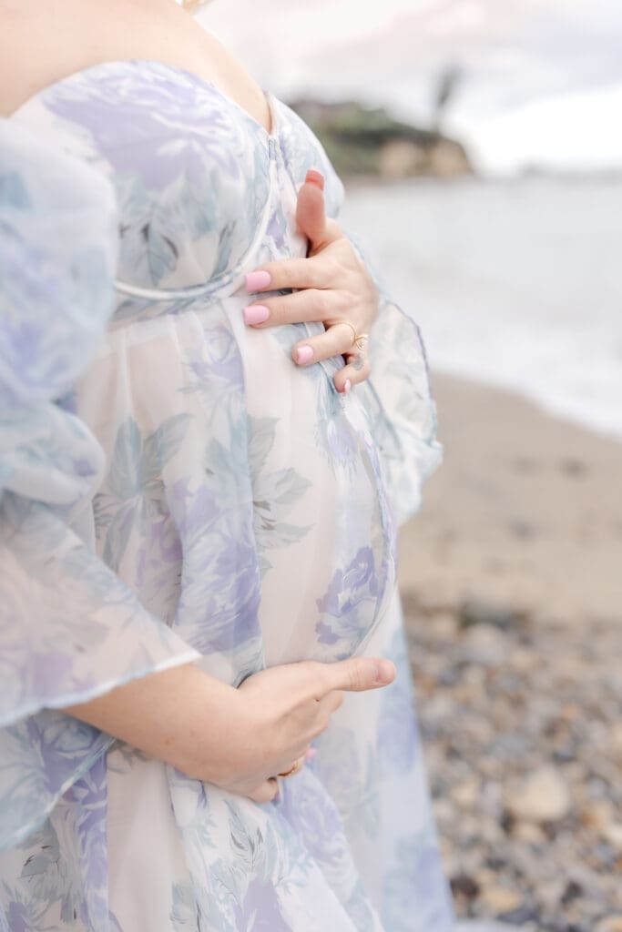 Expecting mother in blue silk gown standing on the Corona Del Mar Beach, luxury maternity portrait