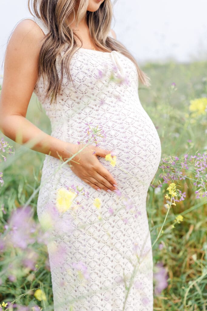 mom holding belly during a maternity session in the flowers