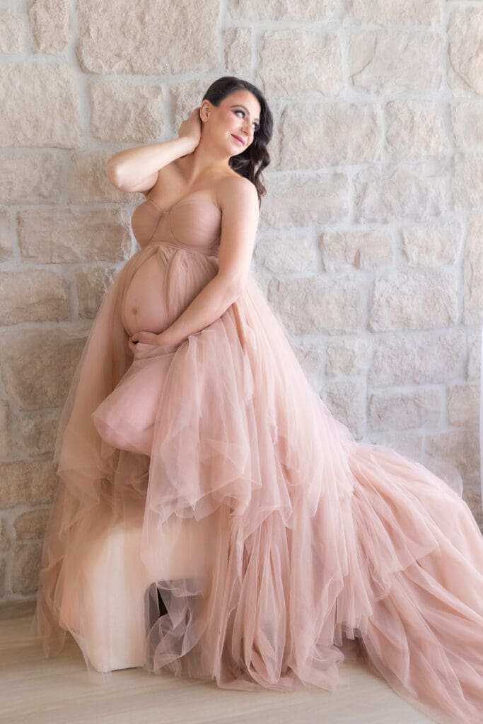 Mom posing with her belly for a maternity session indoors