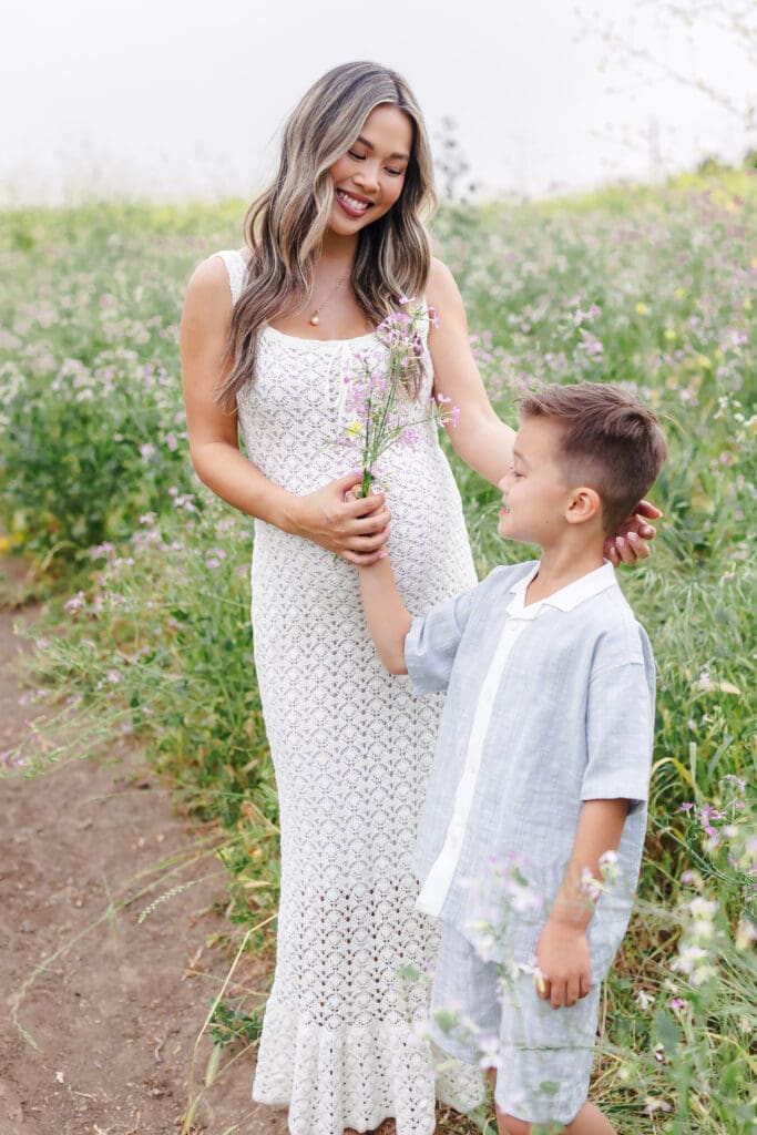 Maternity session mom and son taking flowers and smiling