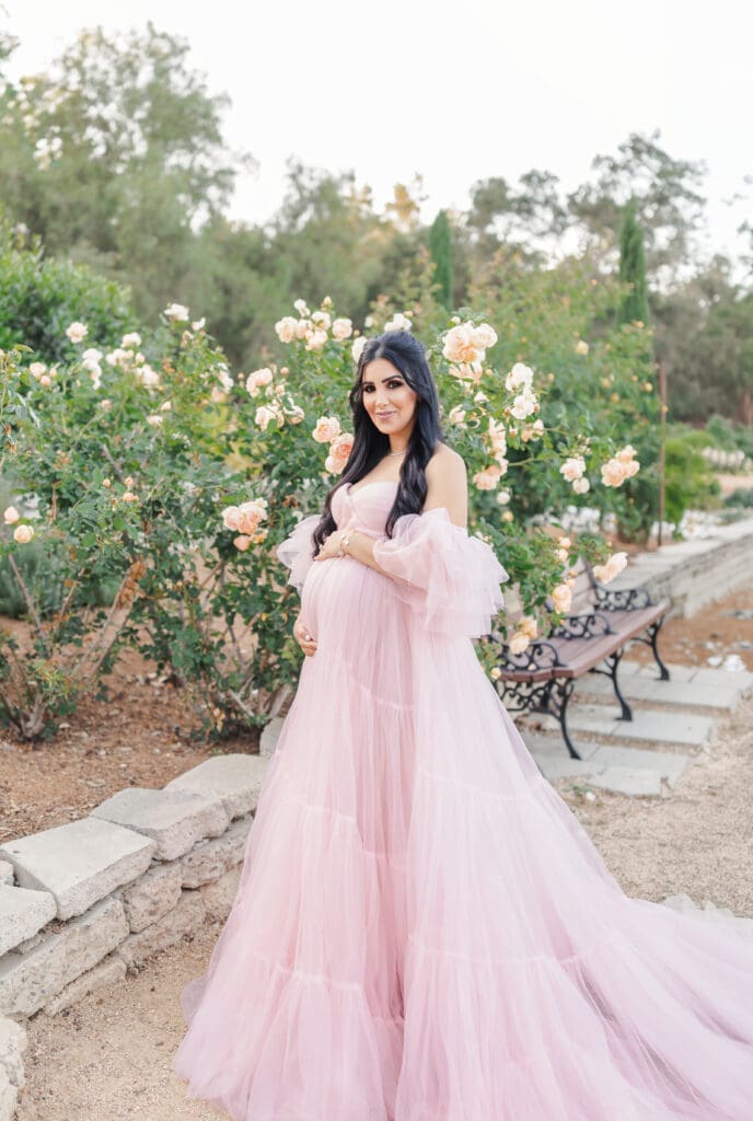 mom in a rose garden in a flowy pink gown 