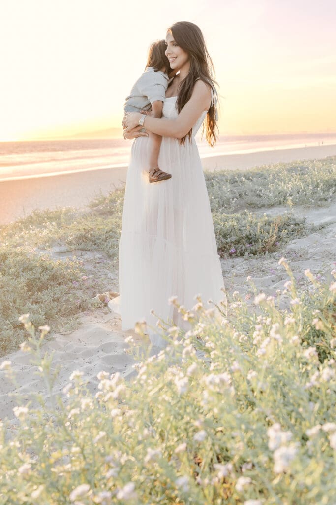 Pregnant mom looking out at the ocean with her toddler 