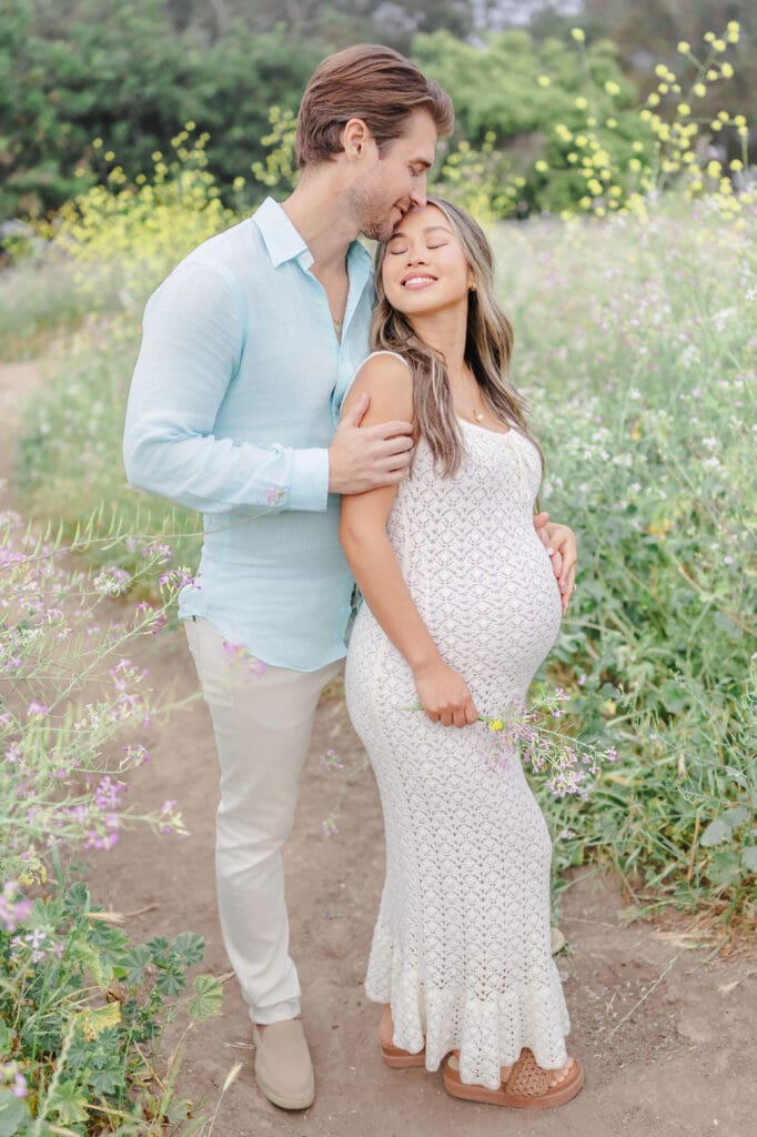 Mom and dad posing and kissing in the flower field 