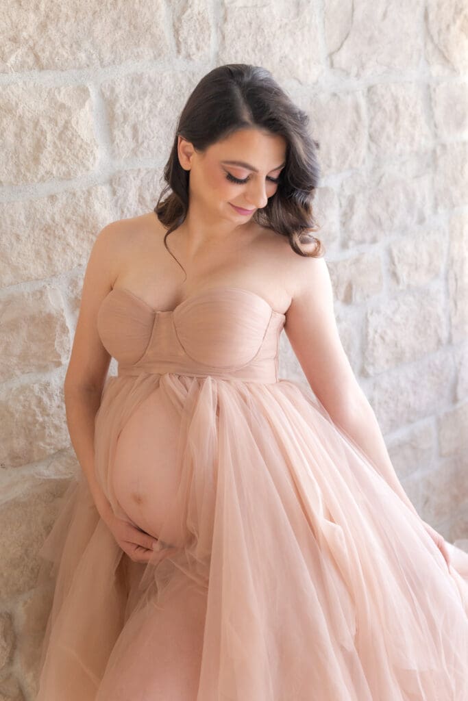 mom looking down and her belly during an indoor maternity session 