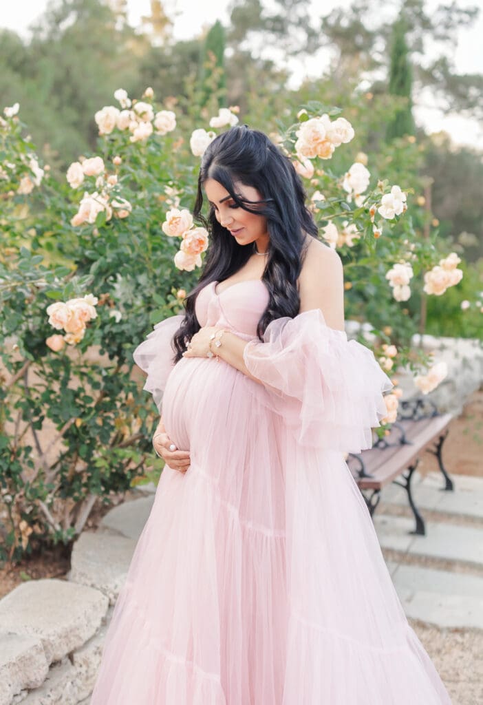 Mom looking down at her bump during a summer maternity session 