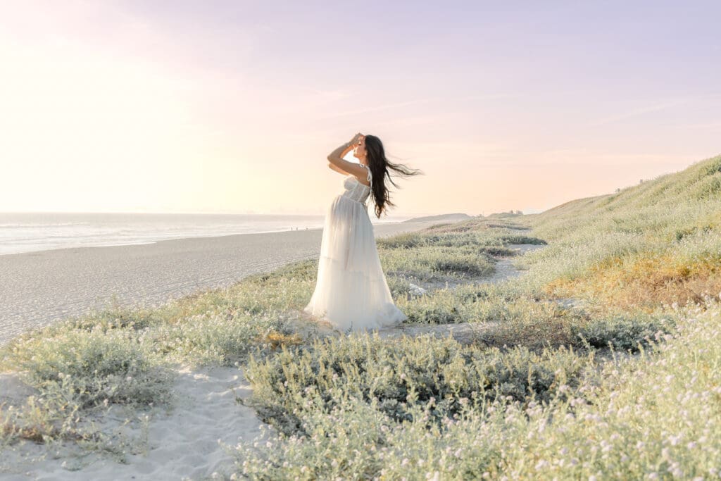 mom on the beach in a flowy white gown 