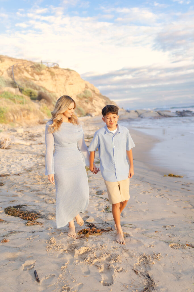 Mom holding sons hand on the sand during a warm summer evening in Newport Beach, California.
