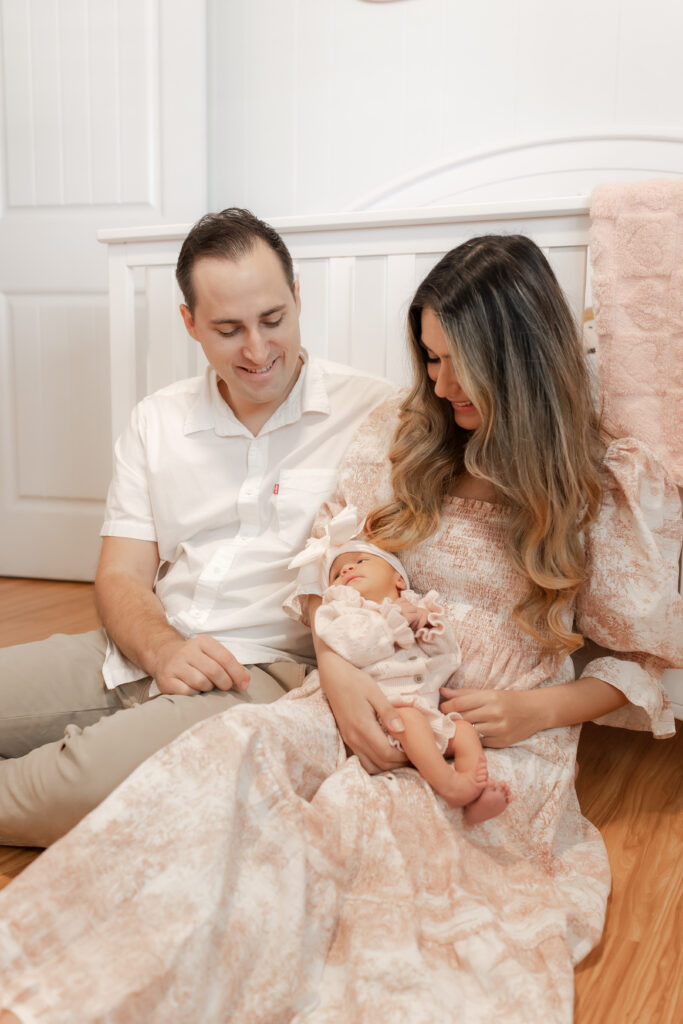 New mom cradling her newborn in natural window light during an in-home session in Newport Beach
