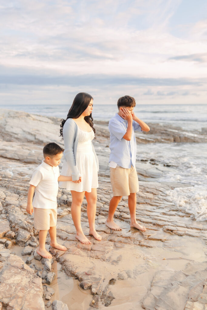 Siblings holding hands while walking along the shoreline at sunset in Newport Beach.